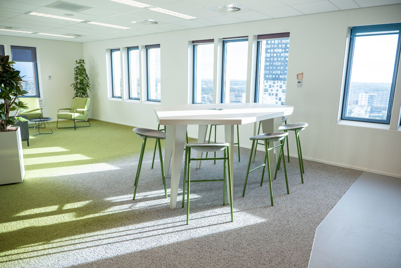 Lichte en flexibel ingerichte werkomgeving van Gasunie met hoge overlegtafel en informele zithoek